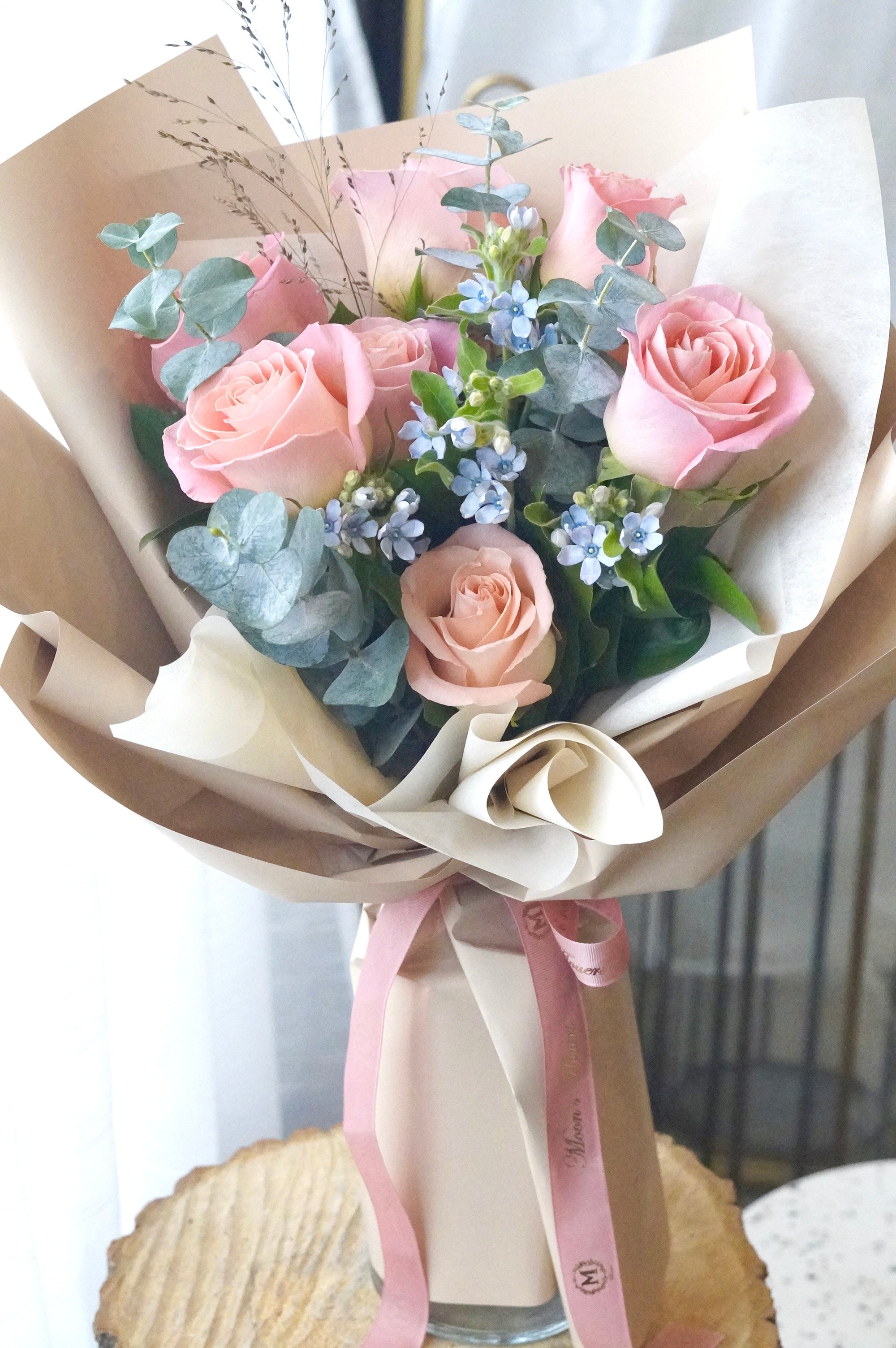 Sky blush rose bouquet featuring soft pink roses with blue accent flowers and fresh greenery