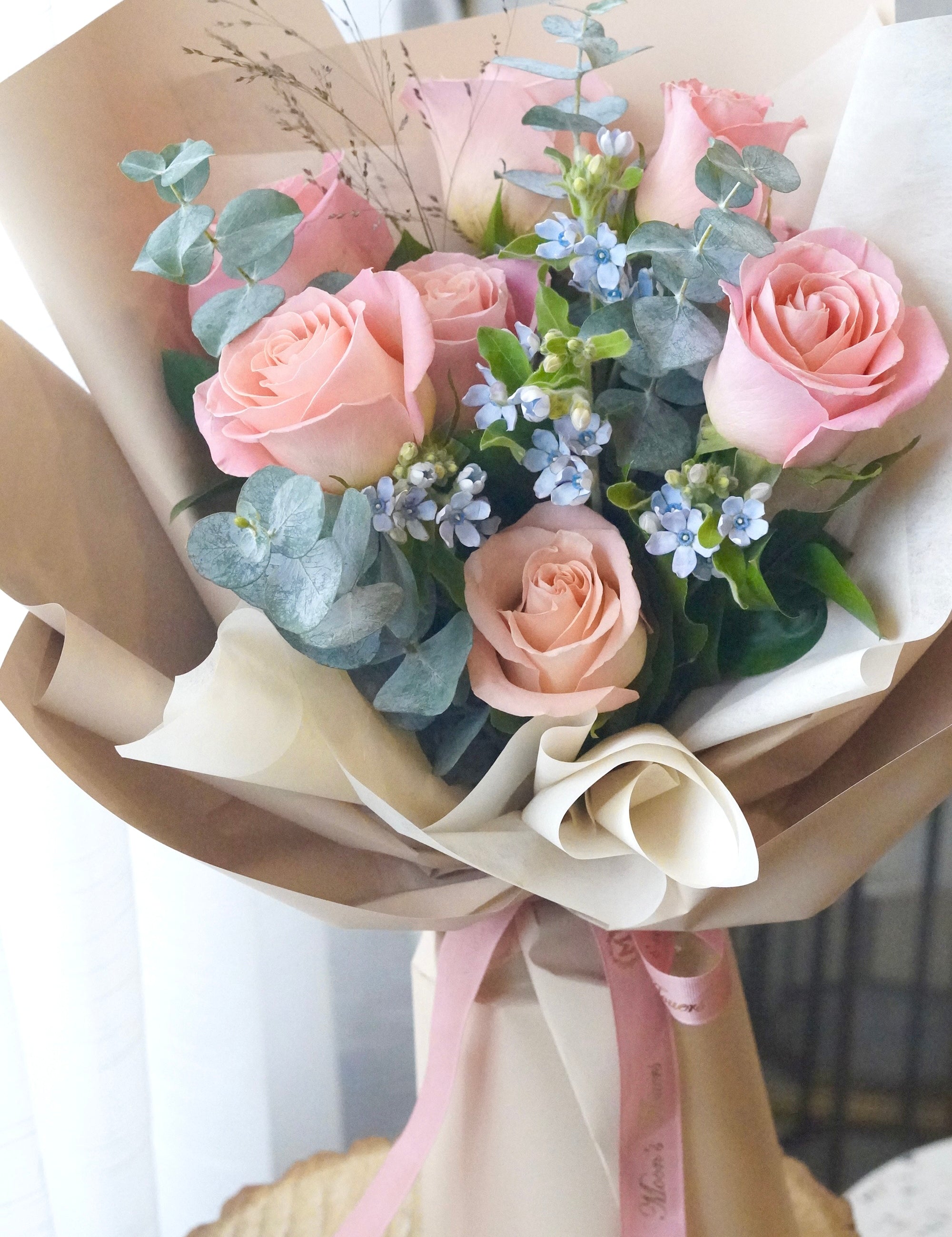 Close-up of blush pink roses with delicate blue accents highlighting soft color contrast