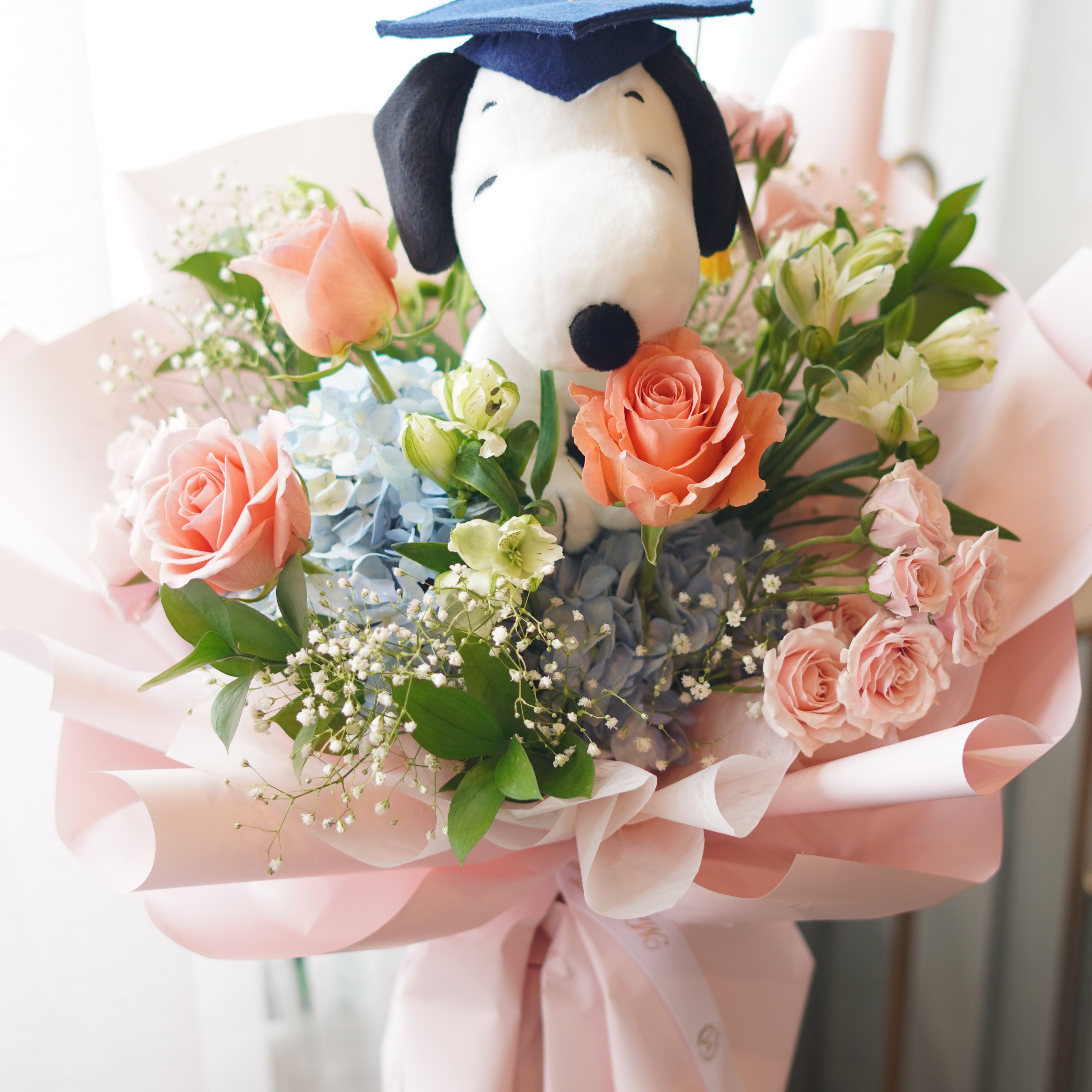 Snoopy graduation bouquet with peach roses and blue hydrangea, soft pink wrapping, Toronto flower delivery