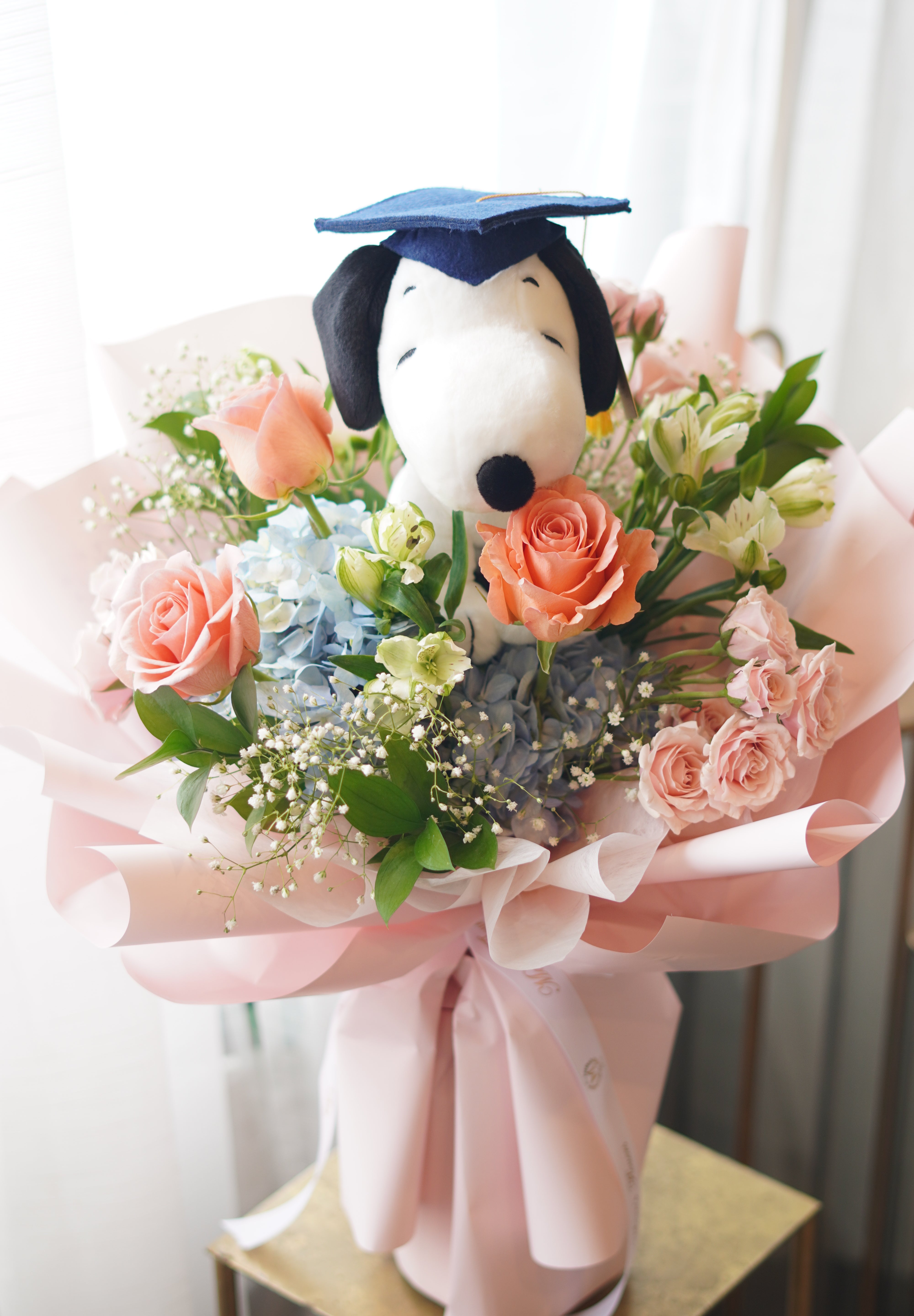 Snoopy graduation bouquet with peach roses and blue hydrangea, soft pink wrapping, Toronto flower delivery