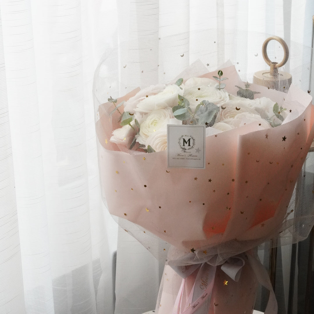 Luxury white ranunculus bouquet with star dotted pink wrapping paper. premium floral design by Moon's Flowers. Available for fast flower delivery in Oakville, Toronto, and the GTA-ideal for unique birthday or Mother's day gift 