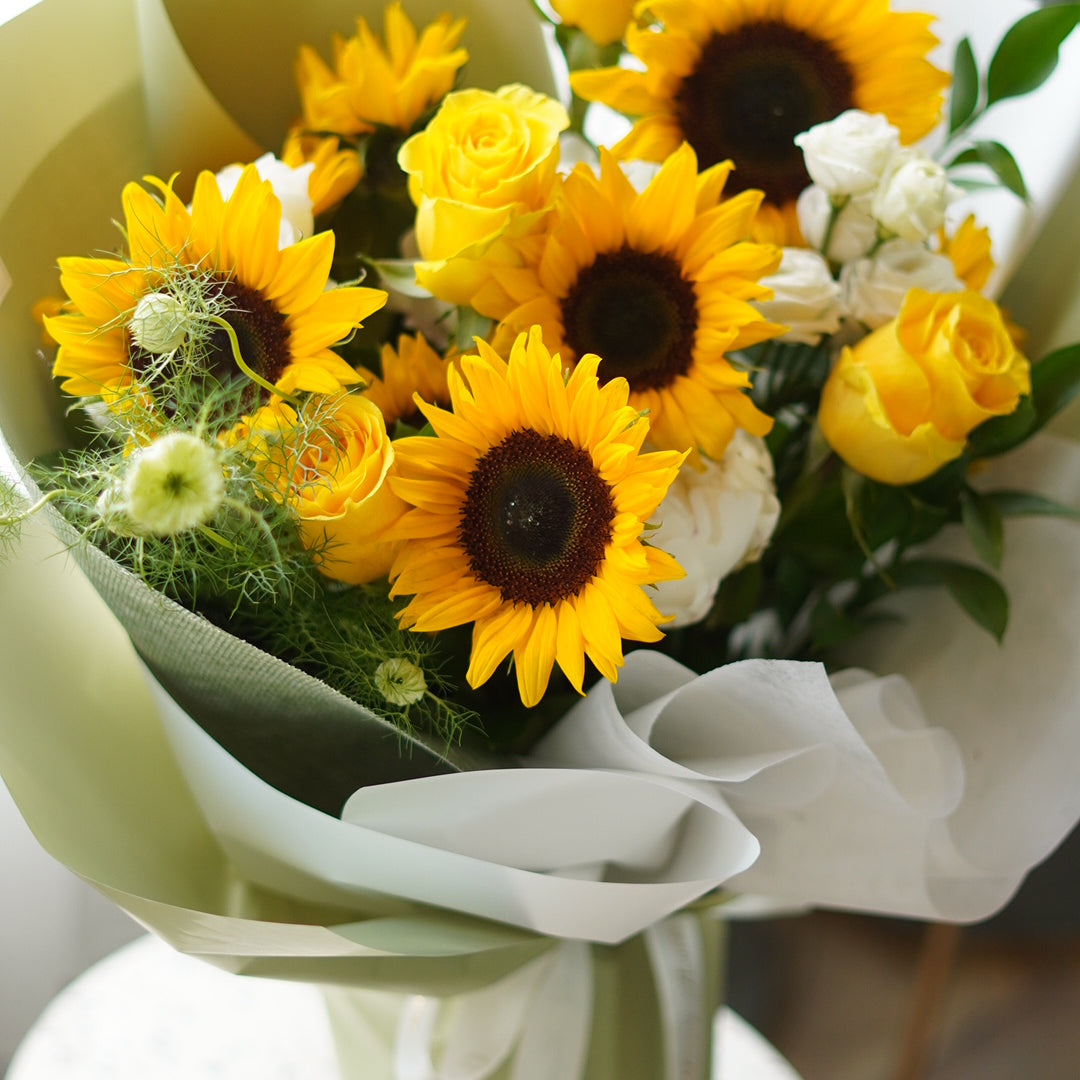 Sunflowers Bouquet from Moon's Flowers featuring fresh yellow sunflowers, roses, and green filler blooms in a premium hand-tied wrap.