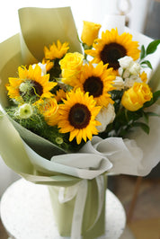 Sunflowers Bouquet from Moon's Flowers featuring fresh yellow sunflowers, roses, and green filler blooms in a premium hand-tied wrap.