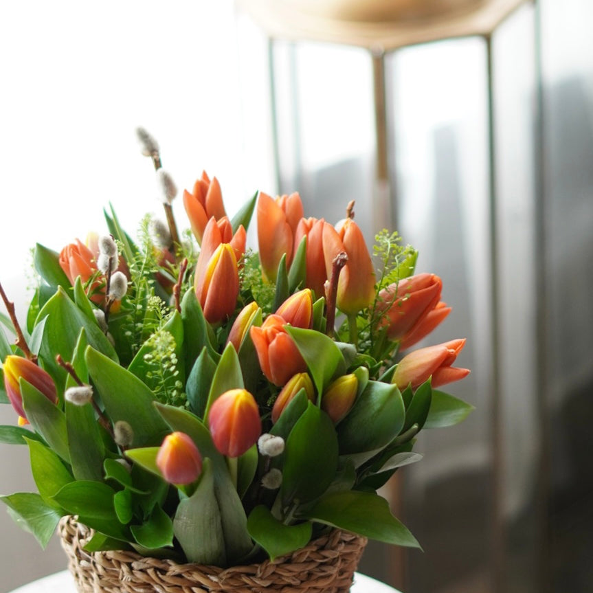 Vibrant tulip arrangement with pussy willow accent in a rustic woven basket