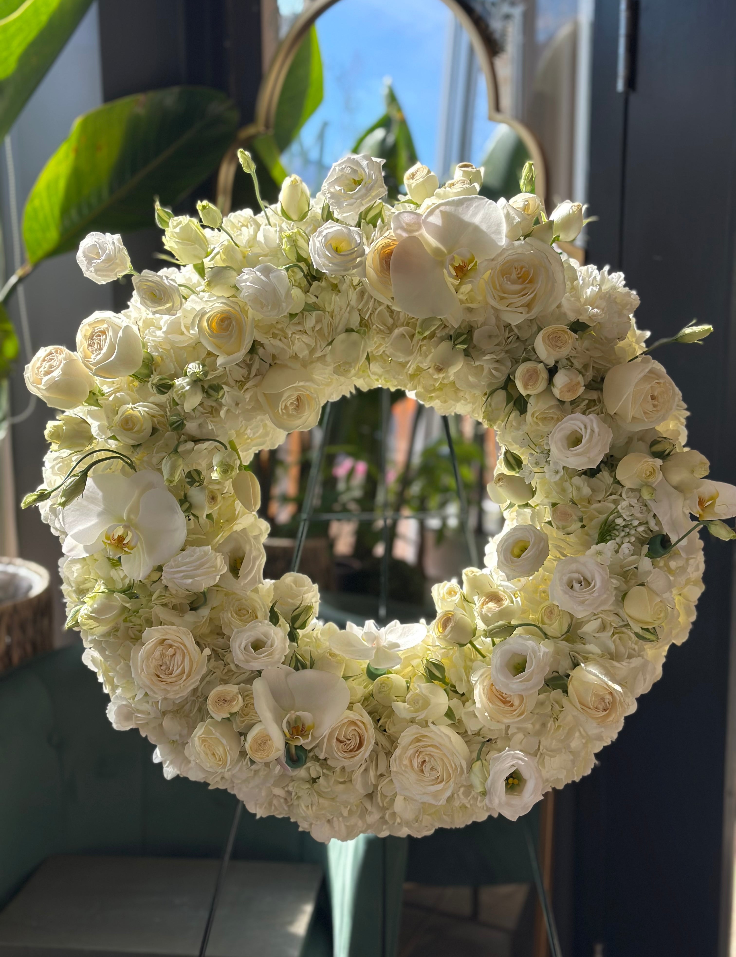 White Grace Funeral Wreath is a funeral wreath made for sympathy. Uses white hydrangeas, white roses, lisianthus, spray roses, and orchids