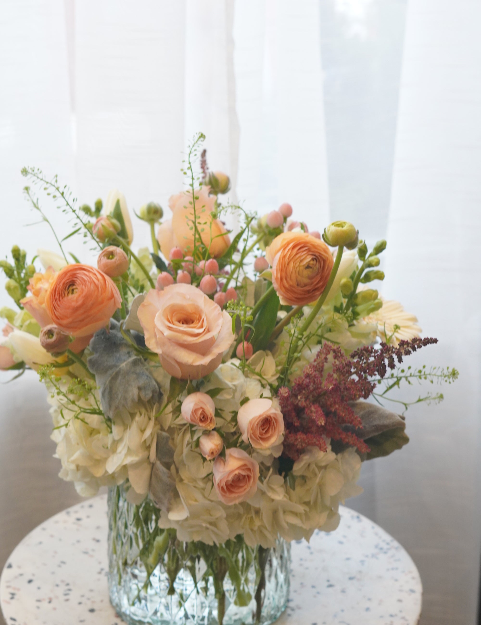 This arrangement also uses a variety of seasonal flowers and greenery to elevate the overall feel and look of the arrangement.