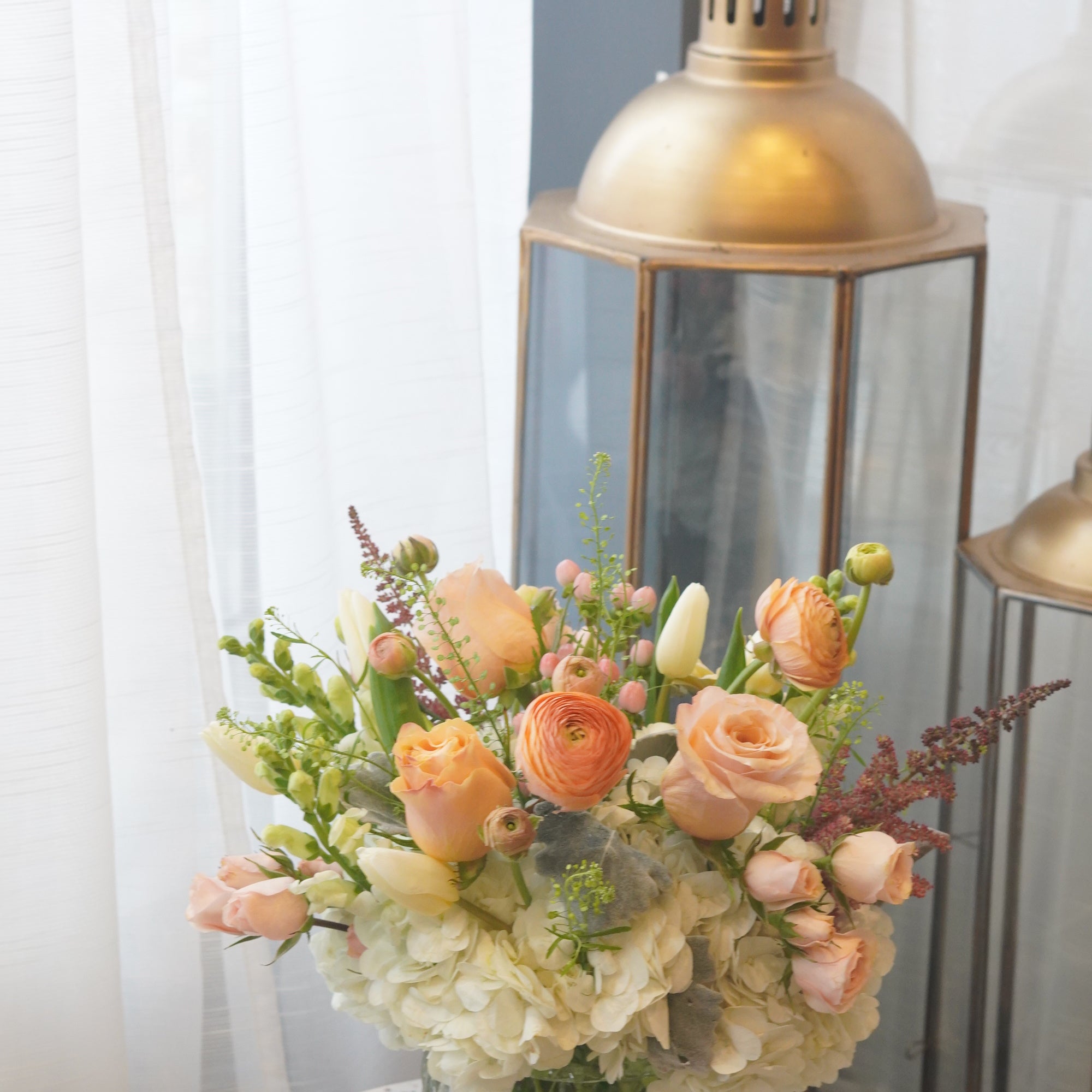The White & Peach Arrangement expertly arranges white hydrangeas with peach accents like roses and ranunculuses to create an elegant yet soft looking arrangement