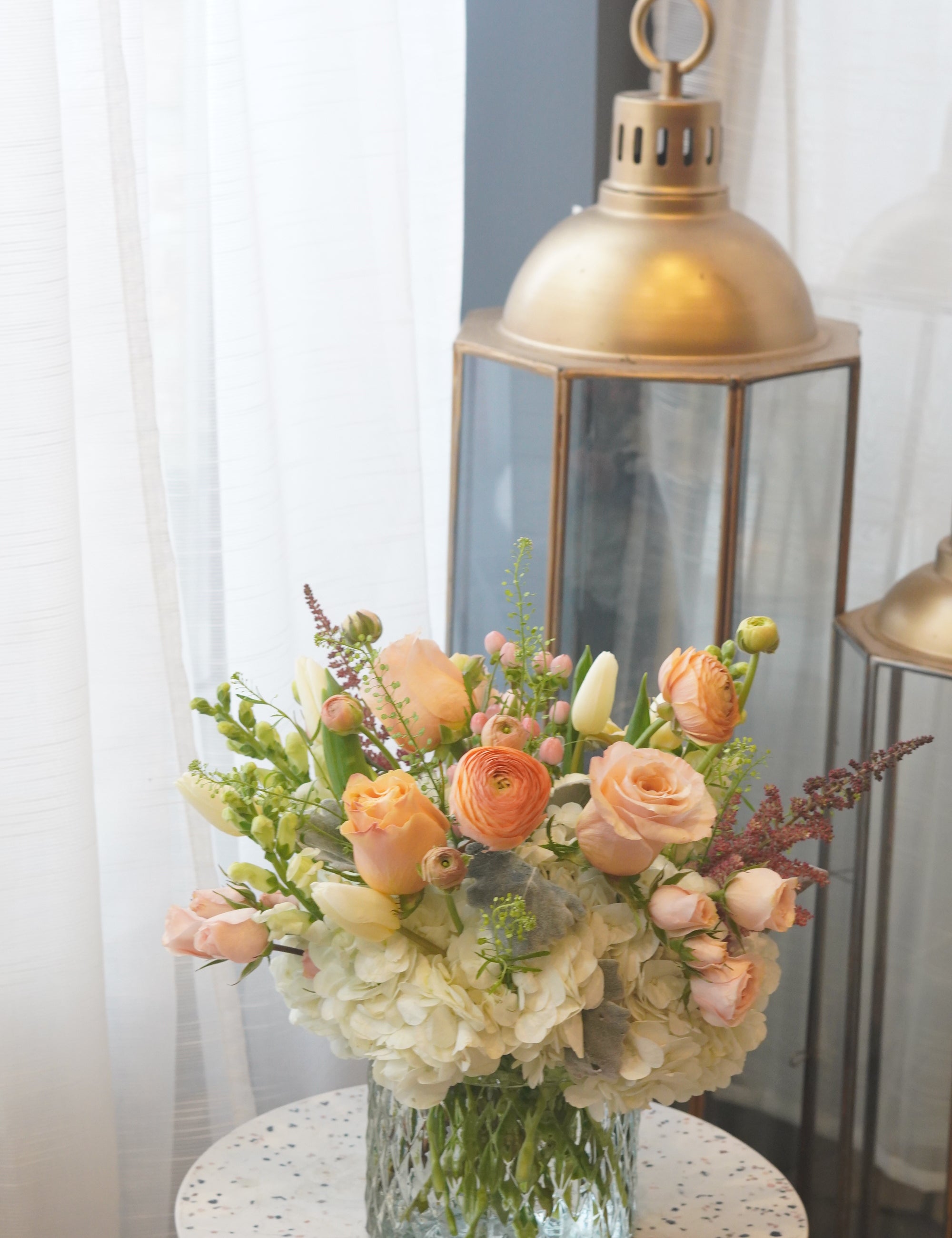 The White & Peach Arrangement expertly arranges white hydrangeas with peach accents like roses and ranunculuses to create an elegant yet soft looking arrangement