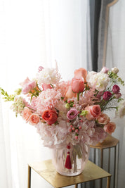 Lush Mother's Day floral arrangement in a glass vase featuring peach roses, pink hydrangeas, and delicate astilbe with a traditional Korean decorative tassel. Premium flower delivery in Toronto and Oakville.
