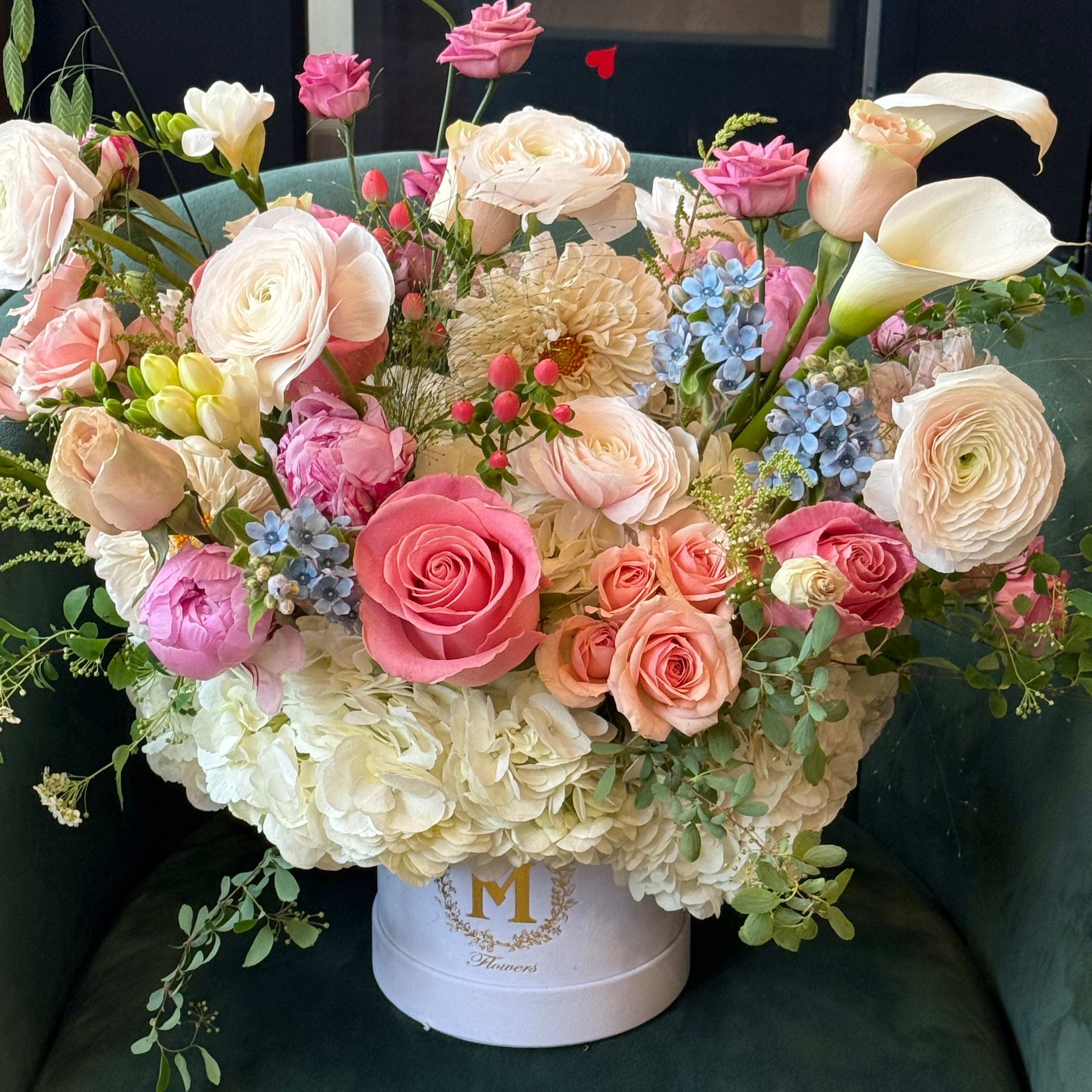elegant pink floral centerpiece with seasonal greenery in a clear decorative carrier