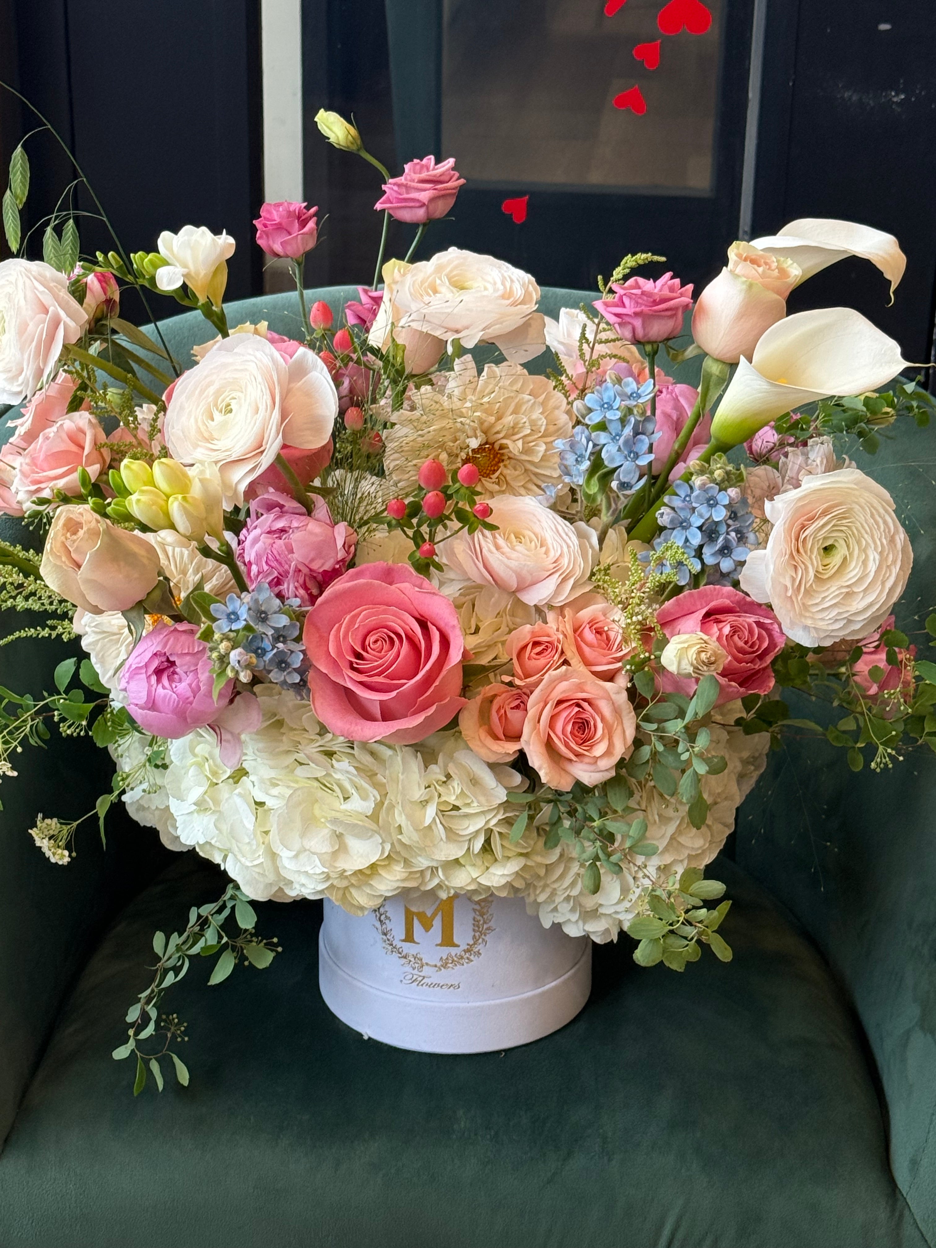 elegant pink floral centerpiece with seasonal greenery in a clear decorative carrier