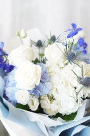 The "Frozen Blooms" bouquet from Moon's Flowers, featuring a winter-inspired color palette of blue and white hydrangeas with white roses