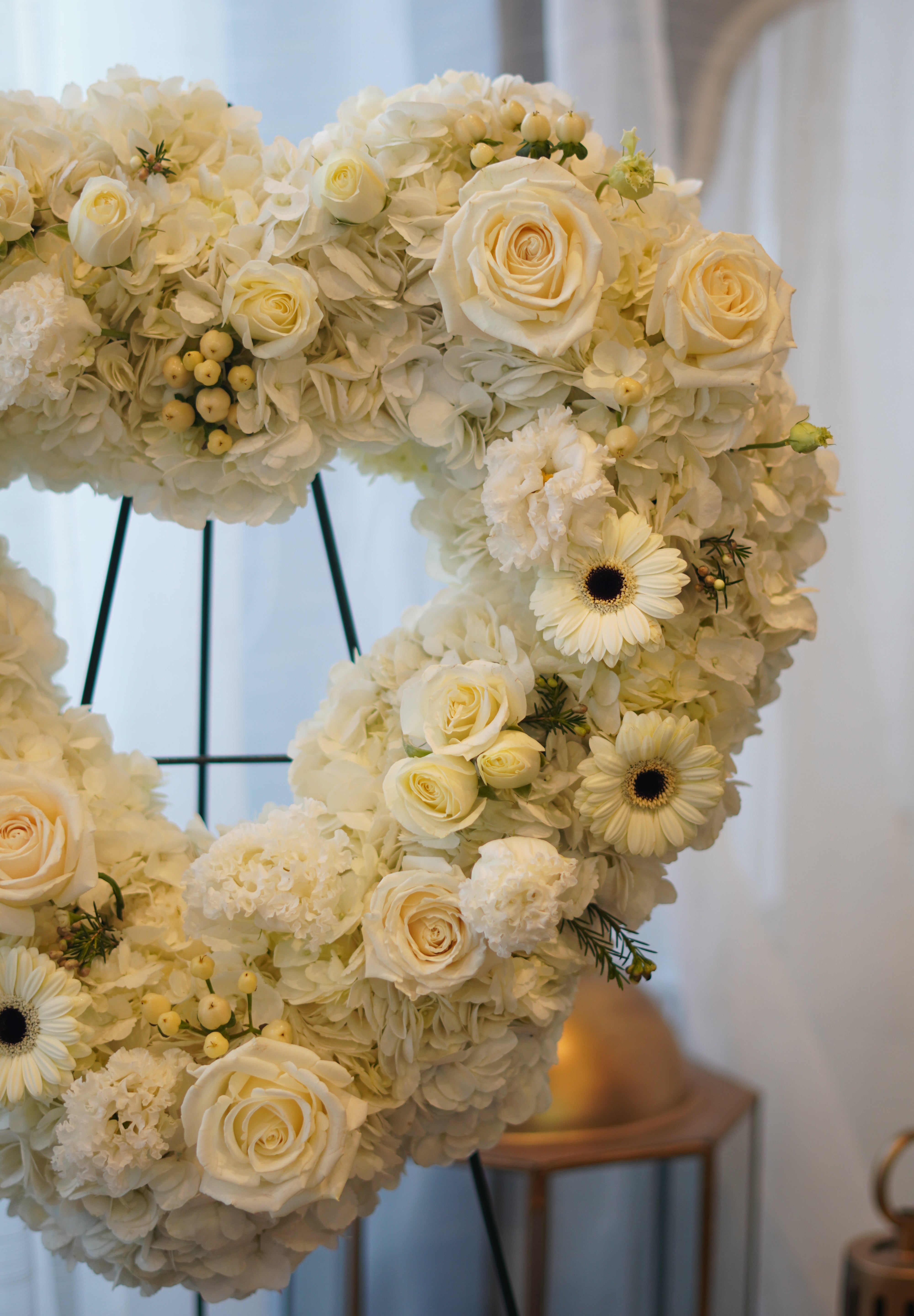 Large white floral heart wreath featuring white roses and greenery, handcrafted by Moon's Flowers Toronto.